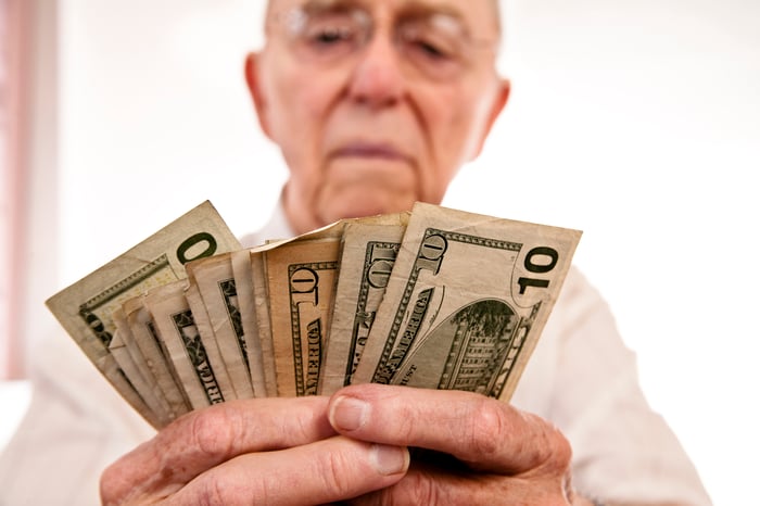 A person counting a stack of different money bills in his hands.